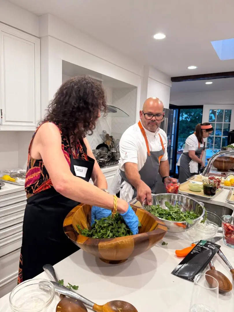 People preparing salad in a kitchen.