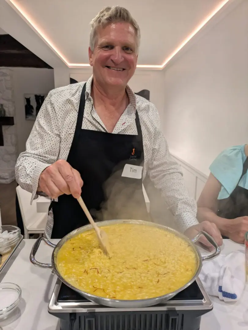Man stirring a large pot of food.