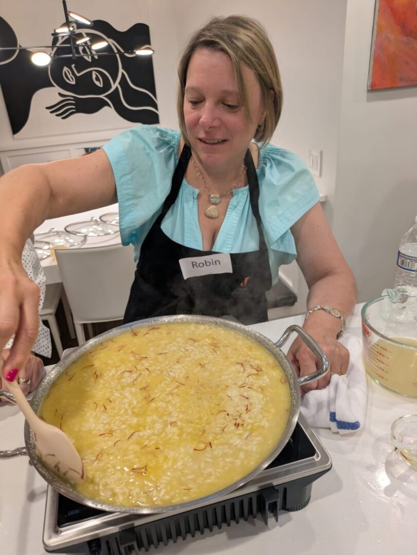 Woman cooking a large pot of risotto.
