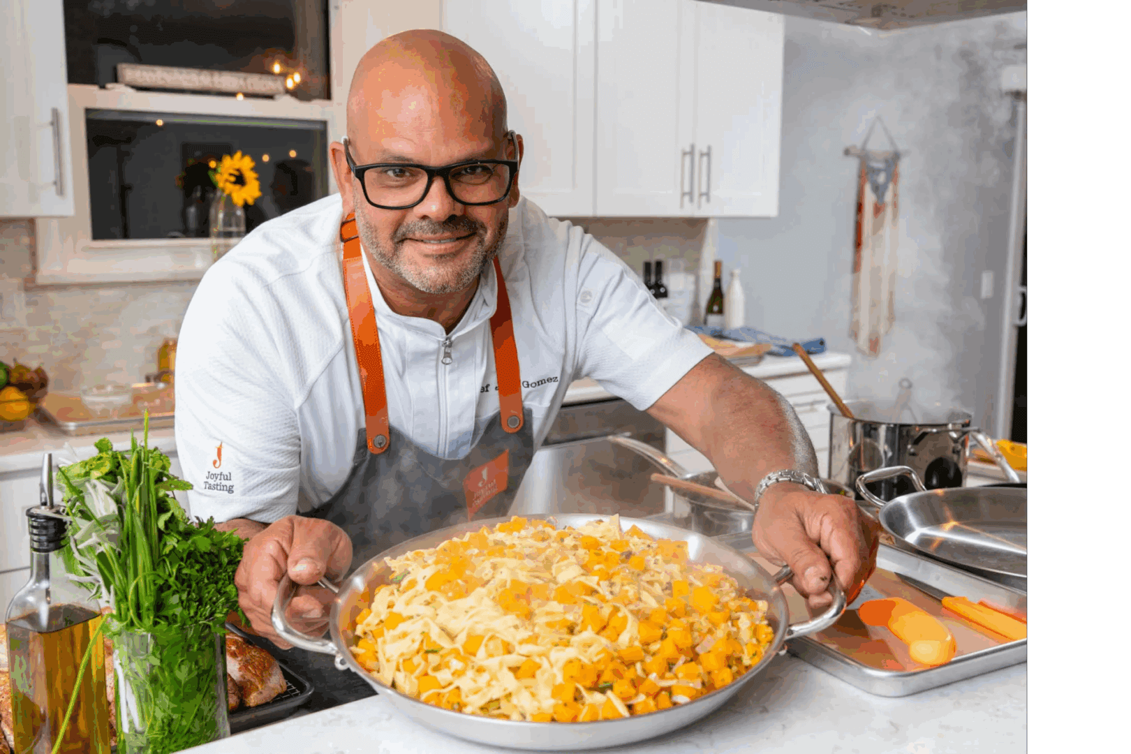 Chef presenting a pasta dish in kitchen.