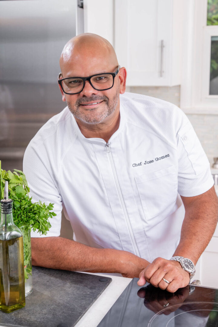 Smiling chef in kitchen with herbs.