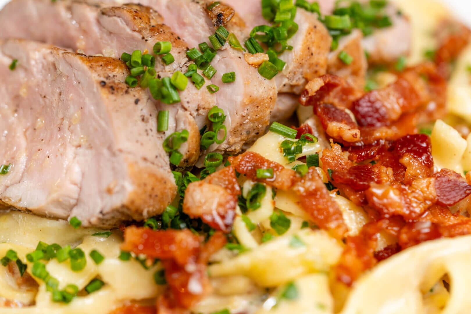 Pasta with sliced pork and crispy bacon.
