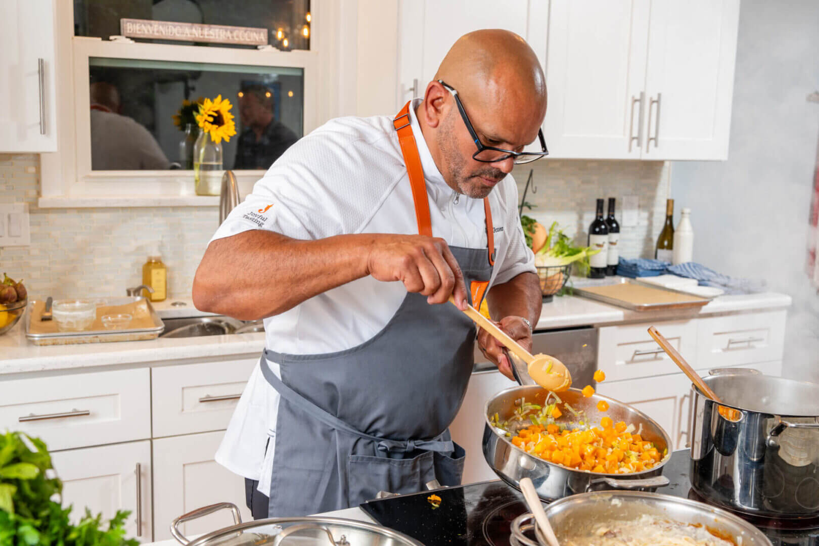 Chef cooking vegetables in a bright kitchen.